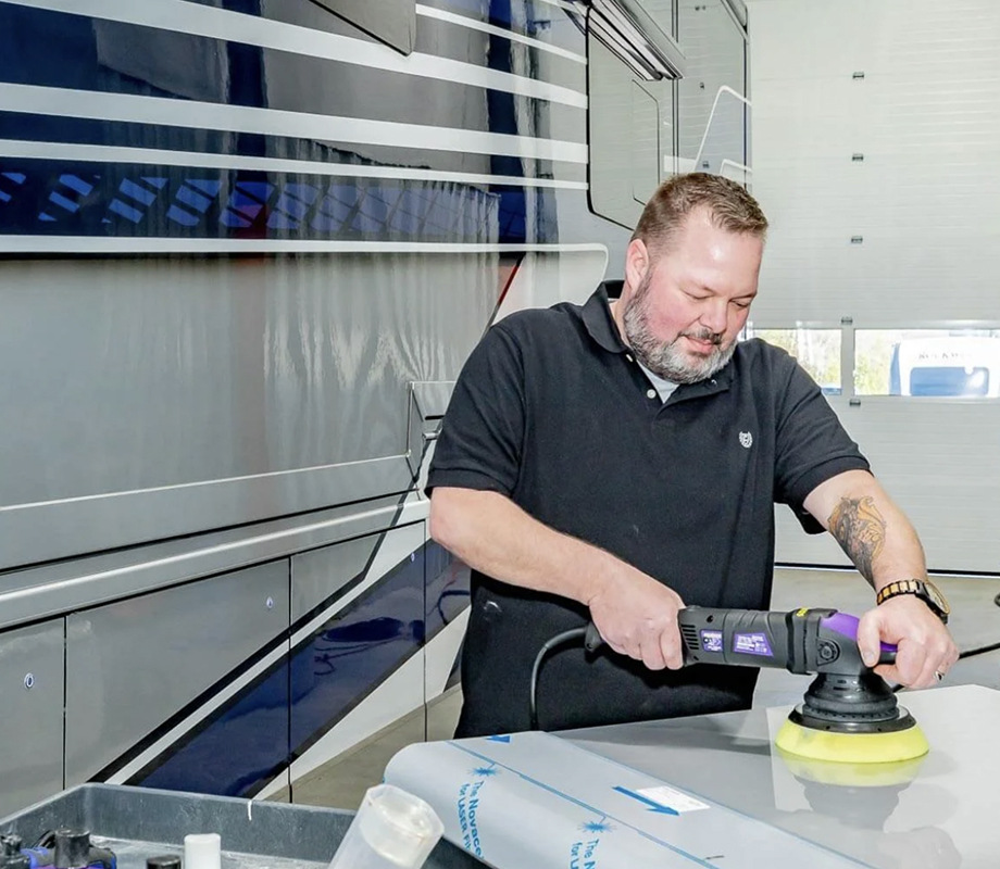 Man using a power buffer to polish the surface of a vehicle inside Hawkins Pointe.
