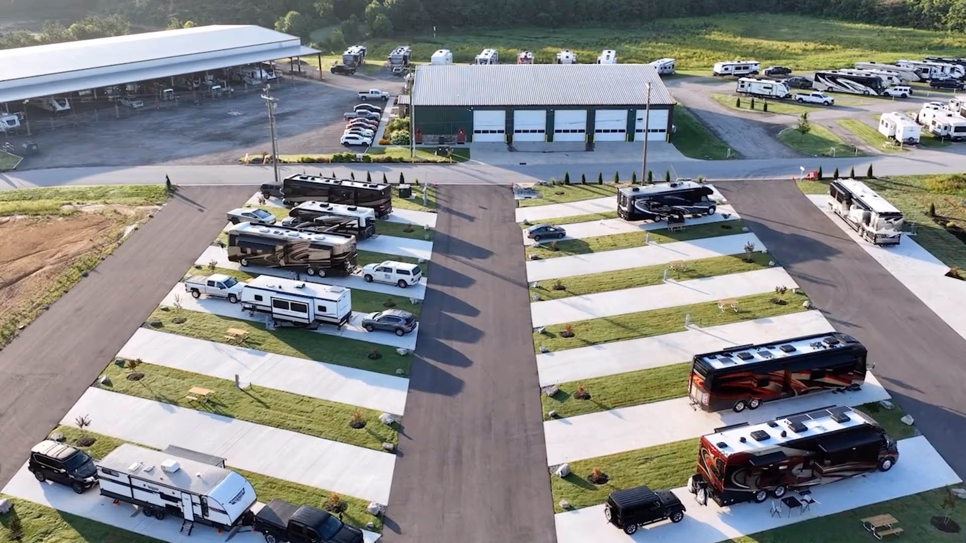 Aerial view the new Executive RV sites in the foreground with green grass patches between them, adjacent to the main building and luxury storage. 