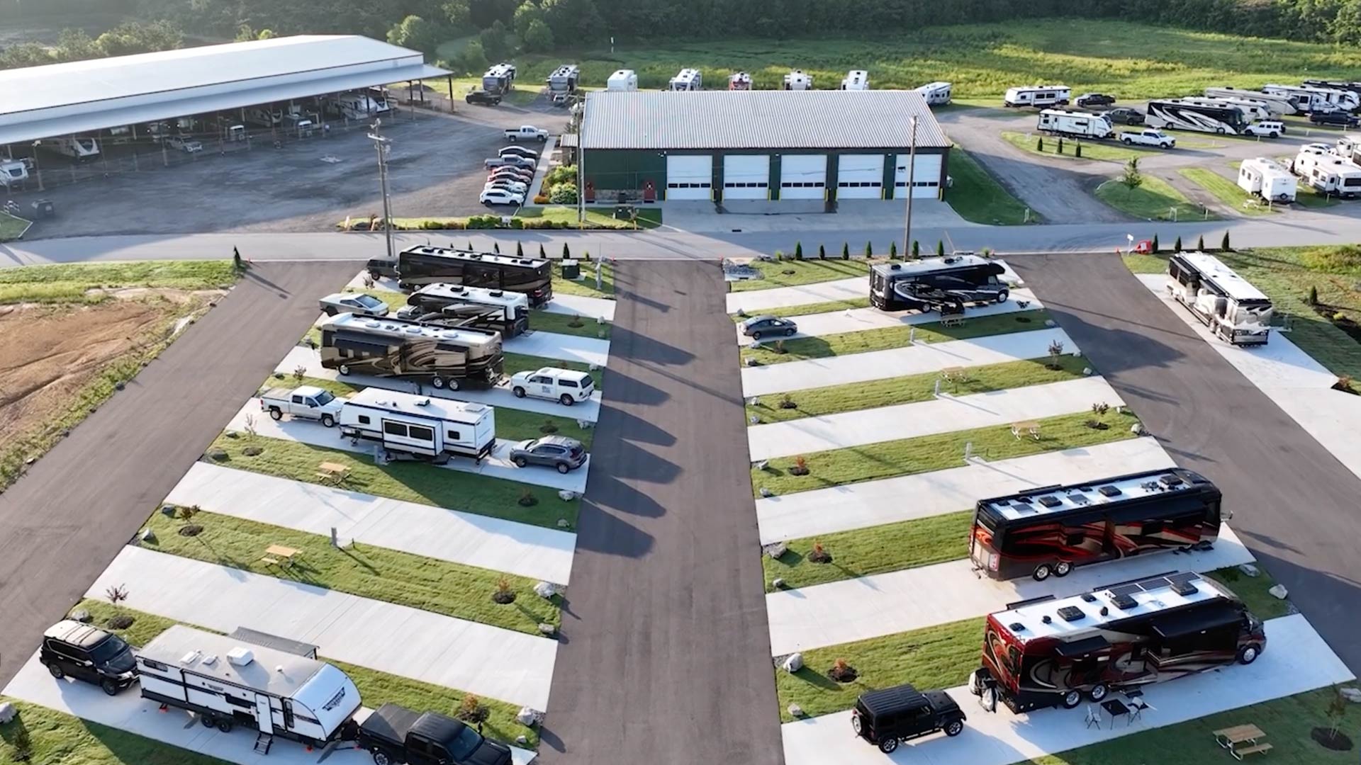 Aerial view the new Executive RV sites in the foreground with green grass patches between them, adjacent to the main building and luxury storage.