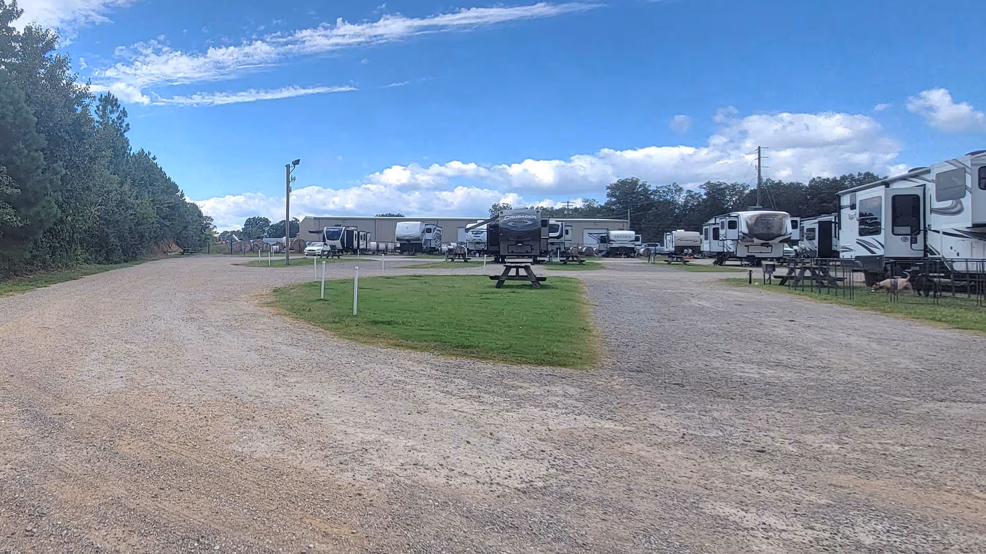 RV campground with gravel roads, several parked trailers, picnic tables on green grass.