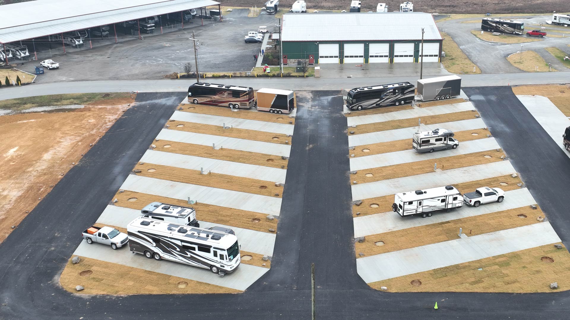 Aerial view of a paved Executive RV sites with motorhomes and trailers parked on adjacent concrete pads.