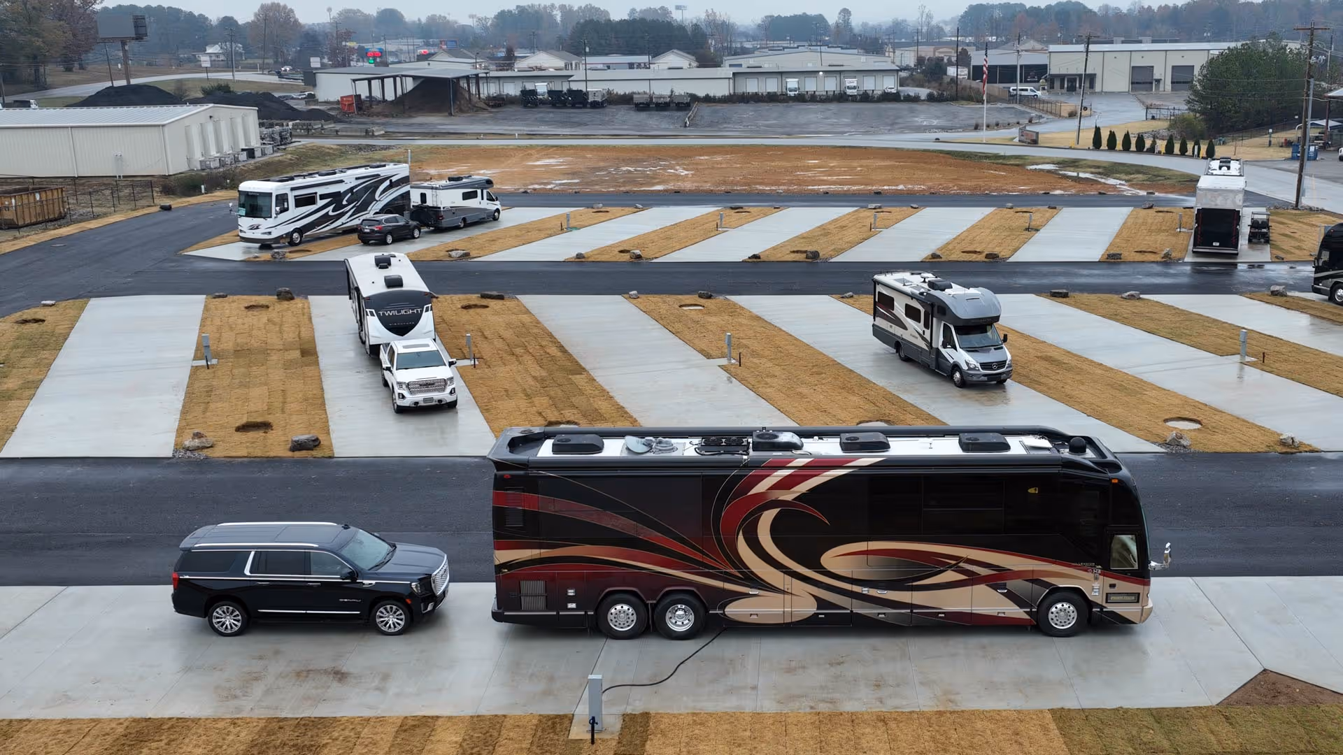 Executive RV site with several recreational vehicles and trucks parked on concrete pads.