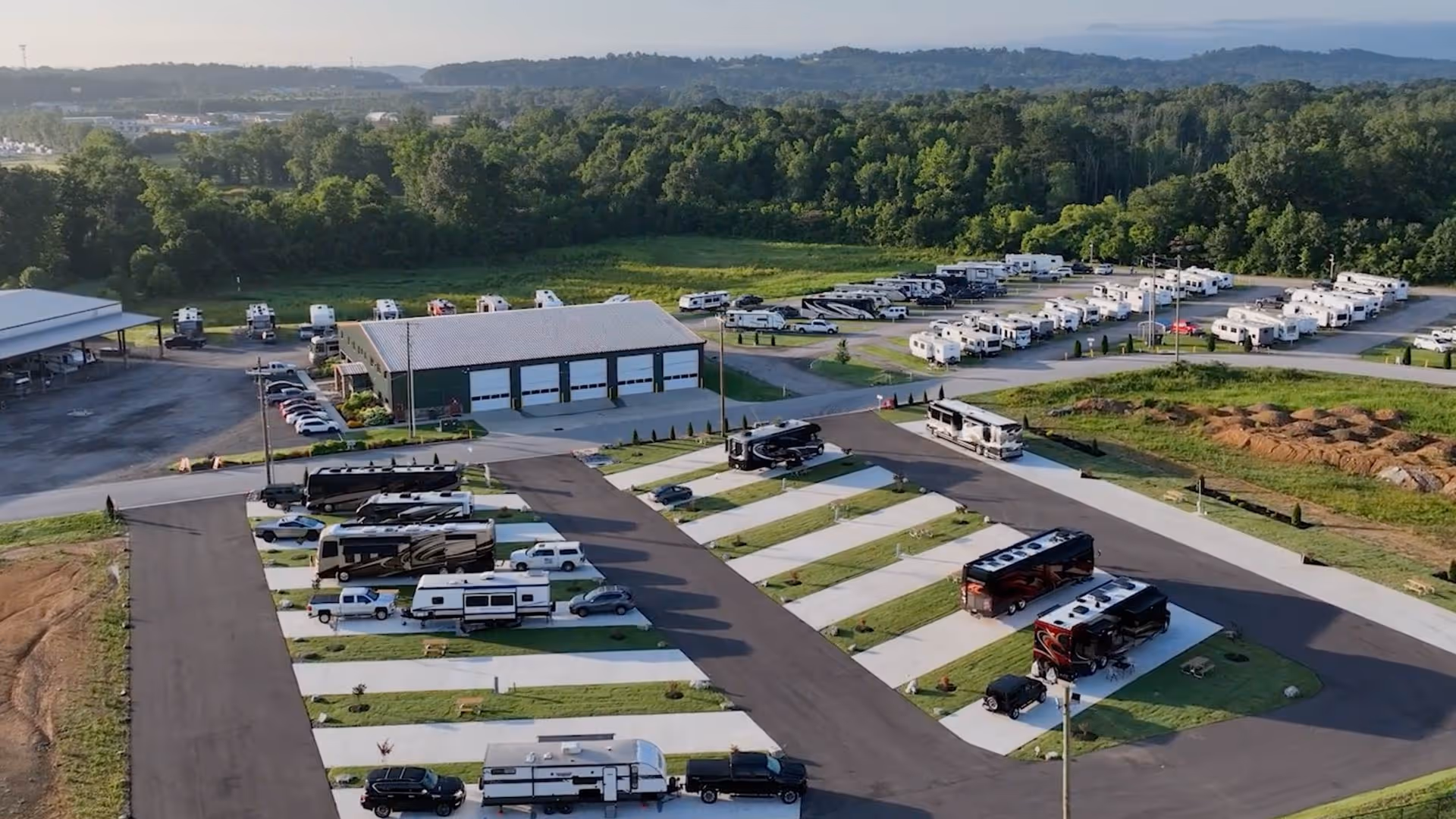 Aerial view of a Hawkins Pointe RV park with multiple motorhomes and trailers parked on paved lots surrounded by green trees and hills.