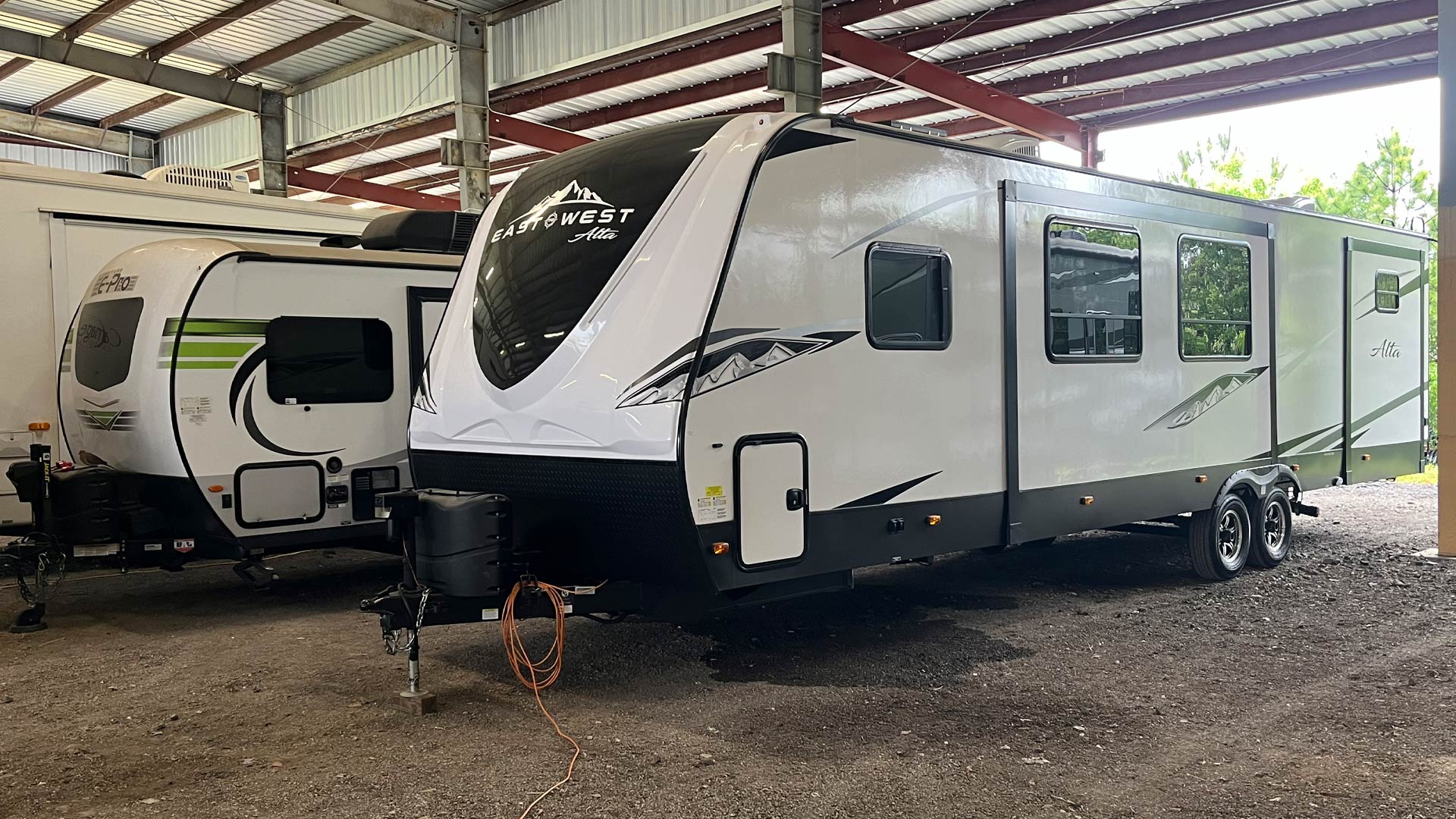White East to West Alta travel trailer with black and gray mountain in our covered storage area.