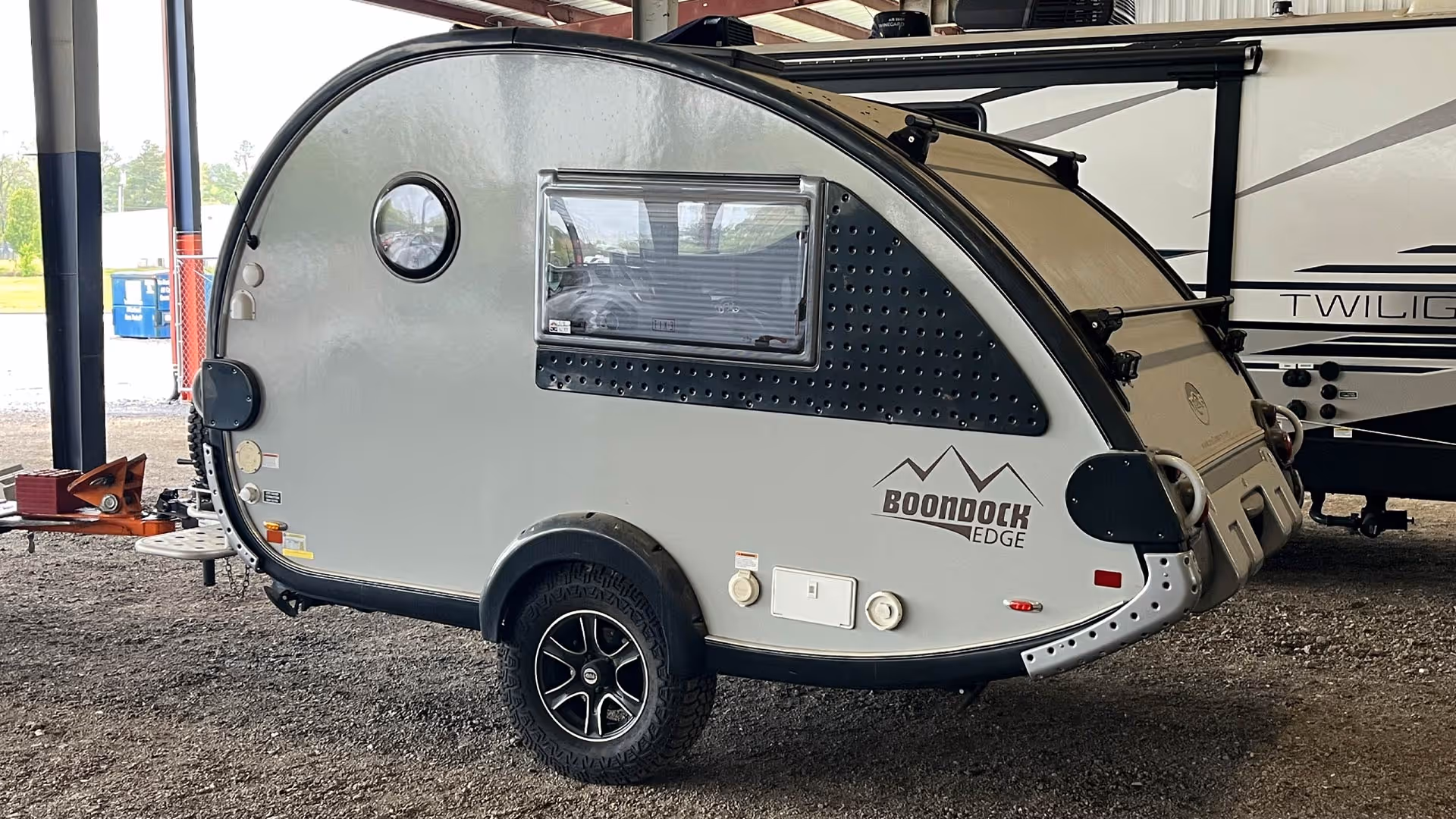 Compact gray teardrop camper trailer with black trim  in our covered storage area.