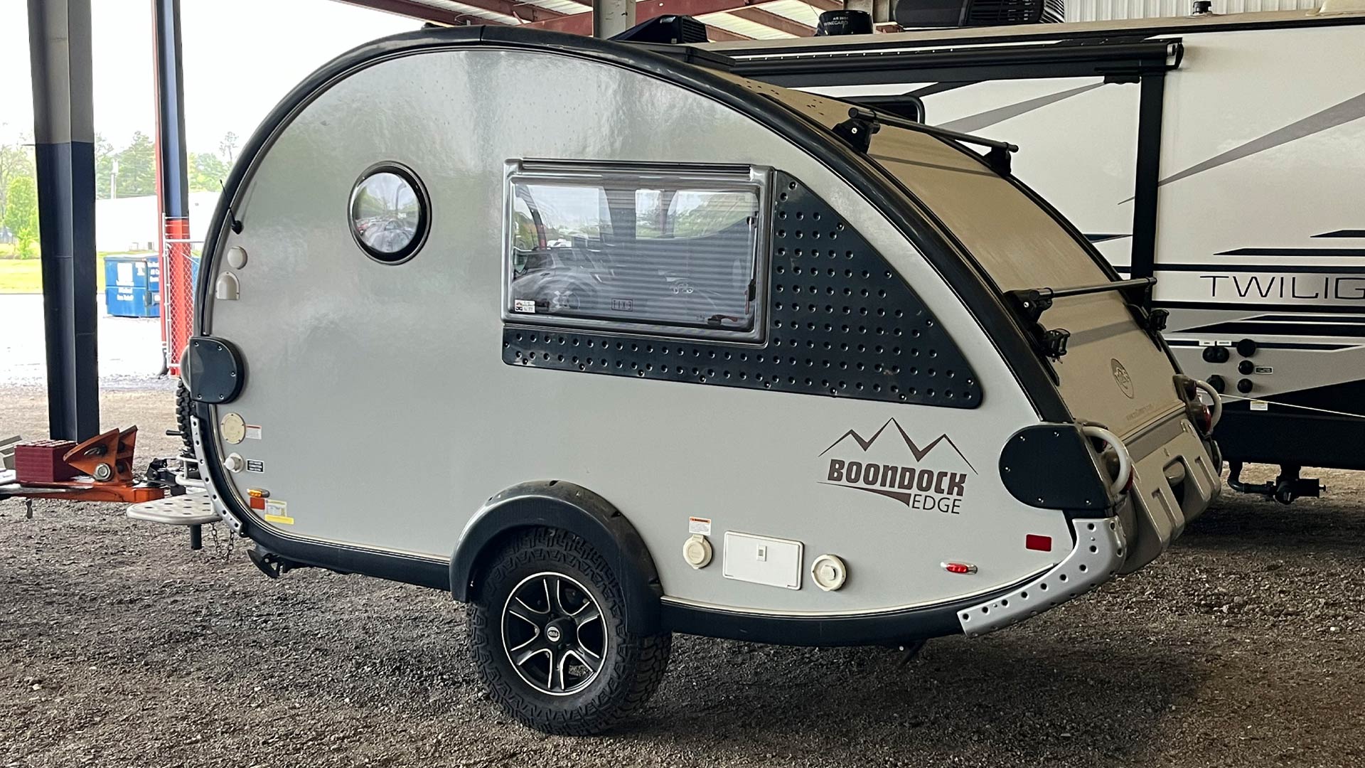 Compact gray teardrop camper trailer with black trim  in our covered storage area.