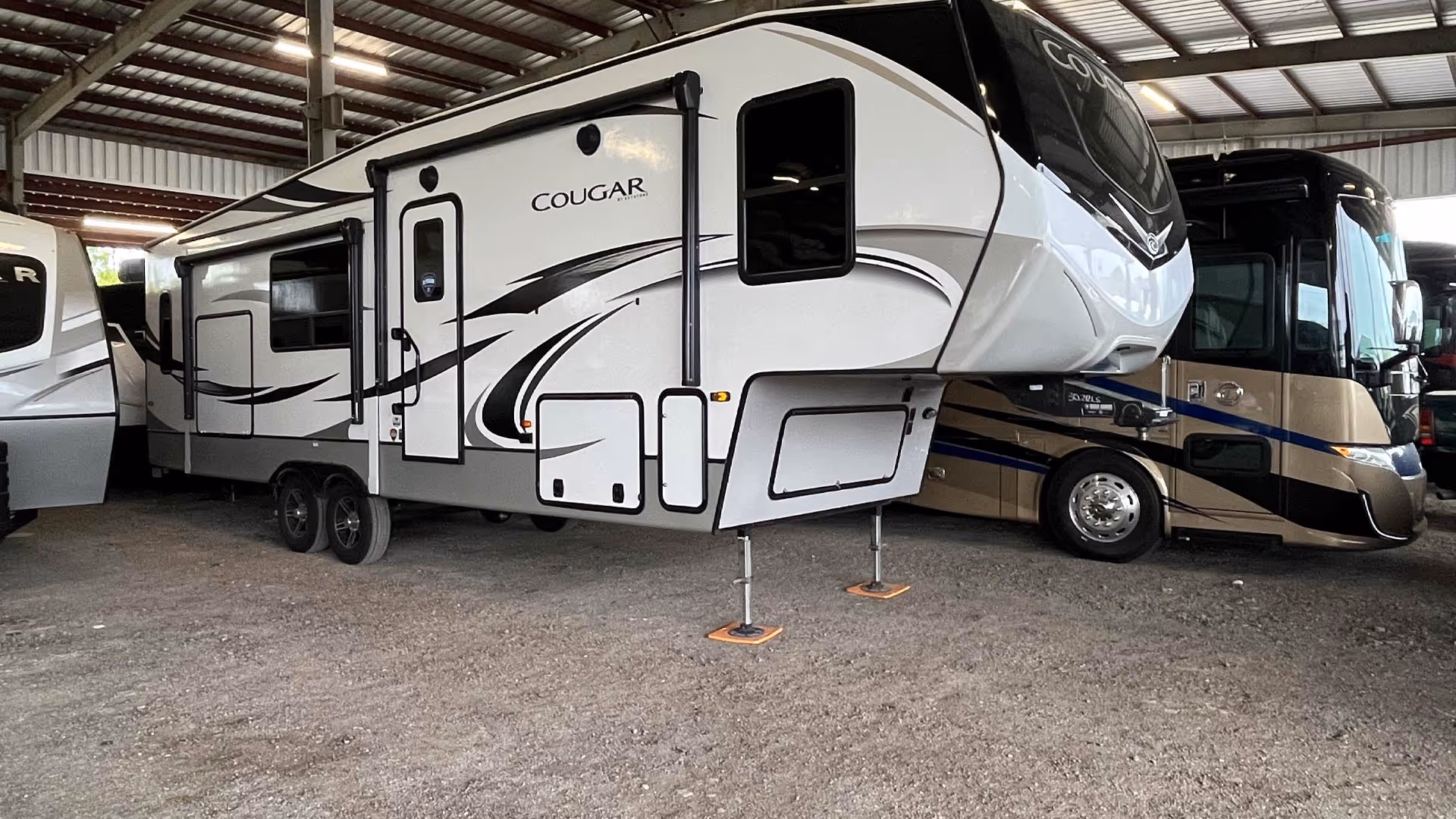White and gray Cougar fifth-wheel RV our covered storage area with other RVs.