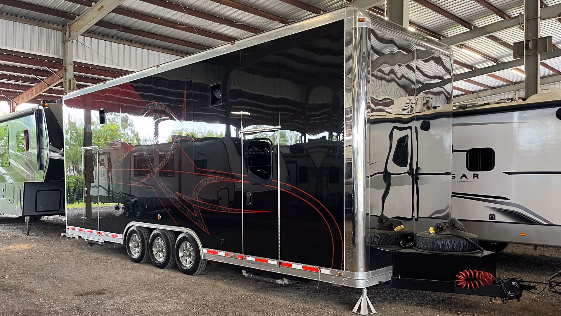 Black enclosed trailer with red abstract designs, inside our covered storage area.