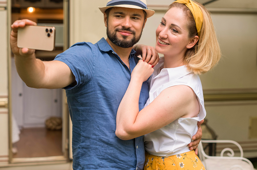 Couple taking a selfie together outside an RV.