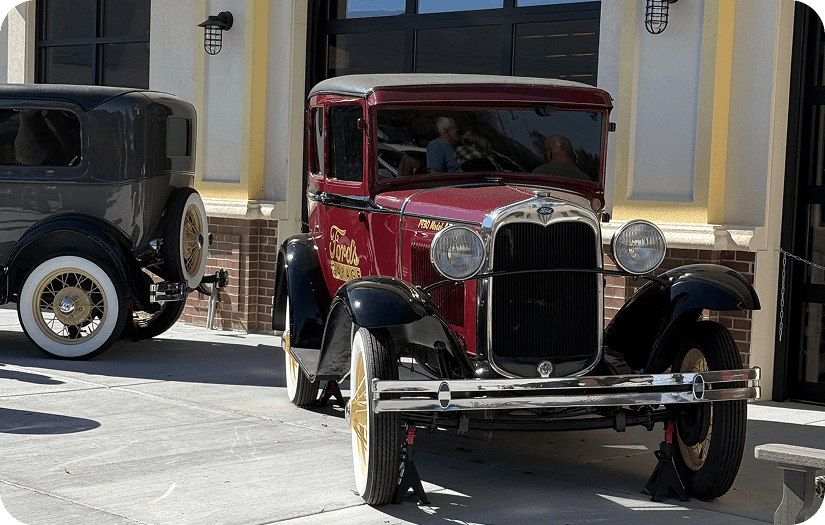 Red vintage Ford with Ford's Garage lettering and a black classic Ford parked outside.