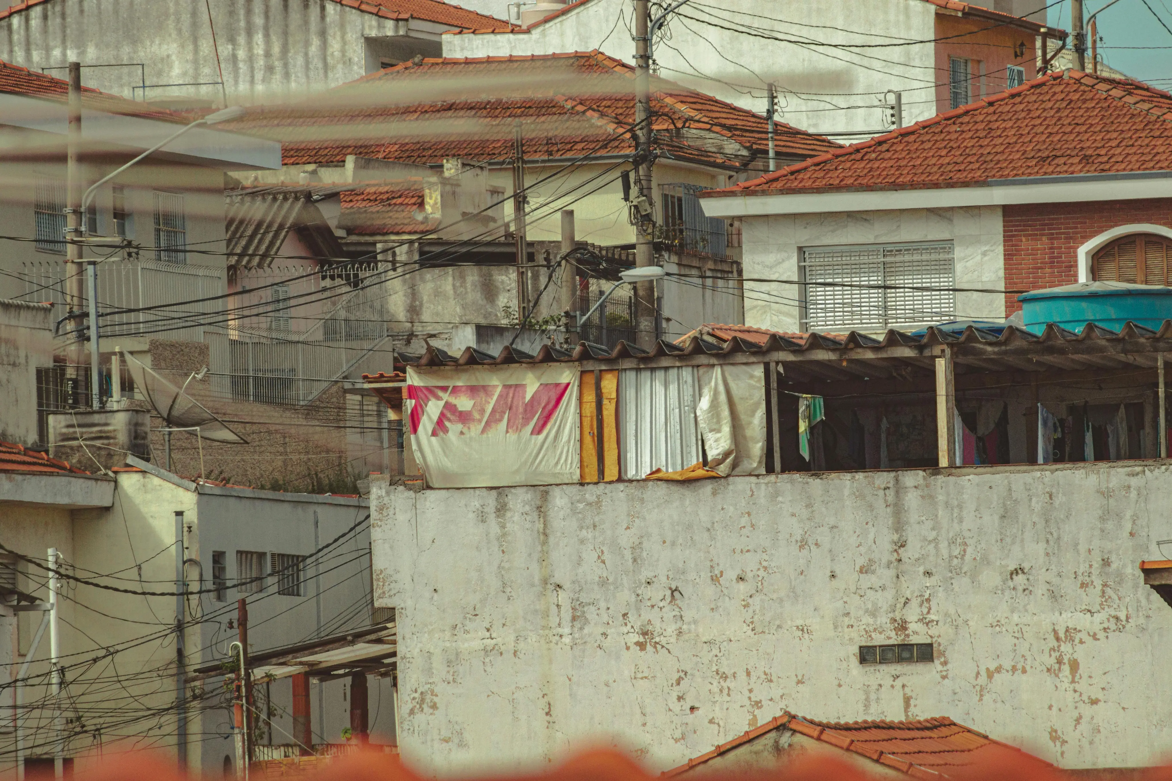 View of tightly packed residential buildings with weathered walls, red tile roofs, and exposed wiring.