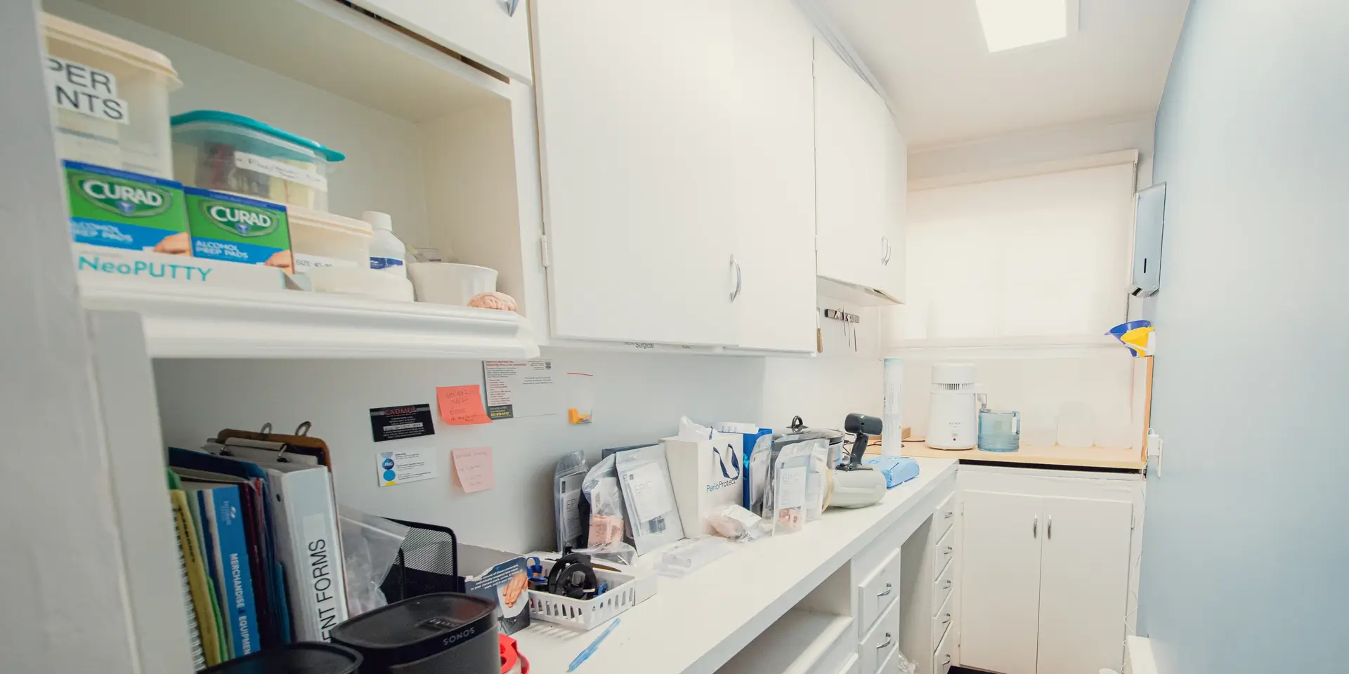 Bright medical storage room with organized supplies, cabinets, files, and dental molds on a counter.