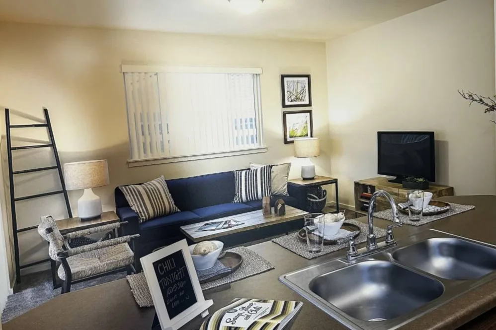 Living room furnished with sofa, coffee able, and tv with view over kitchen sink