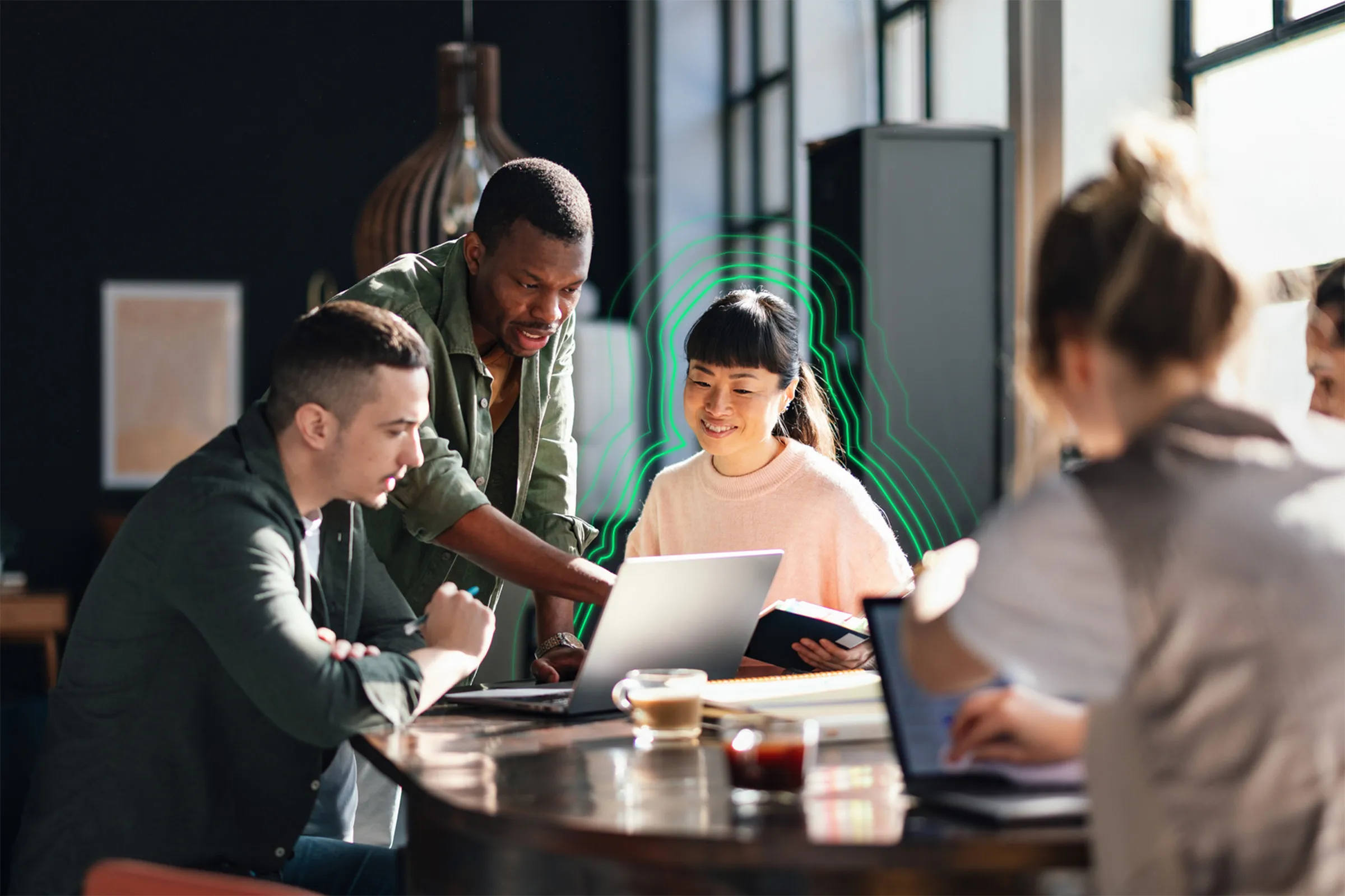 A group of people sitting around a table looking at a laptop.