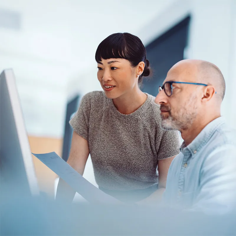 A man and a woman looking at a computer screen.