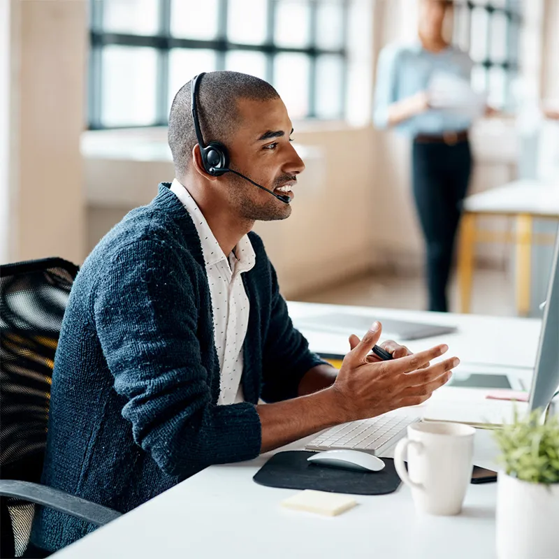 A man wearing a headset sitting in front of a computer.
