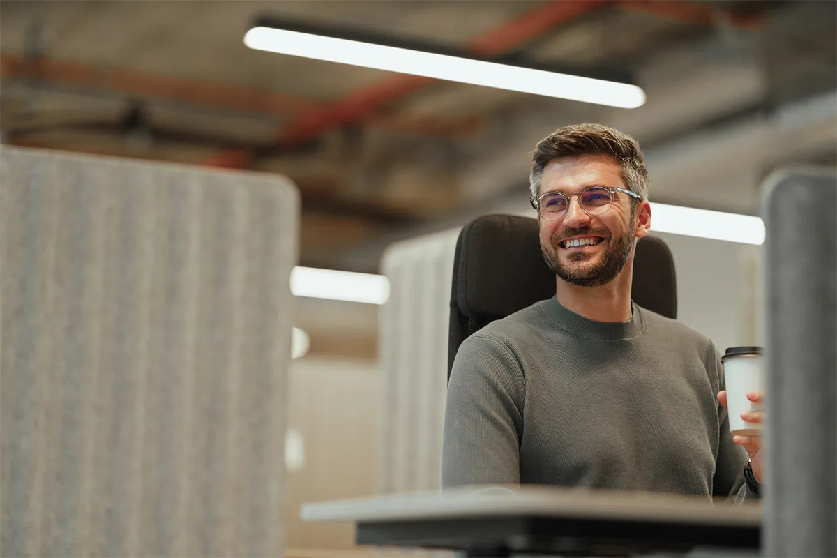 A man sitting at a desk with a cup in his hand.