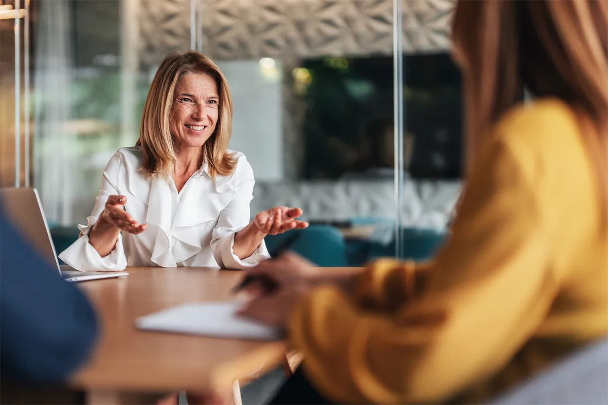 A woman sitting at a table talking to another woman.