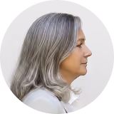 Profile of a middle-aged woman with silver-gray hair looking ahead on a white background.