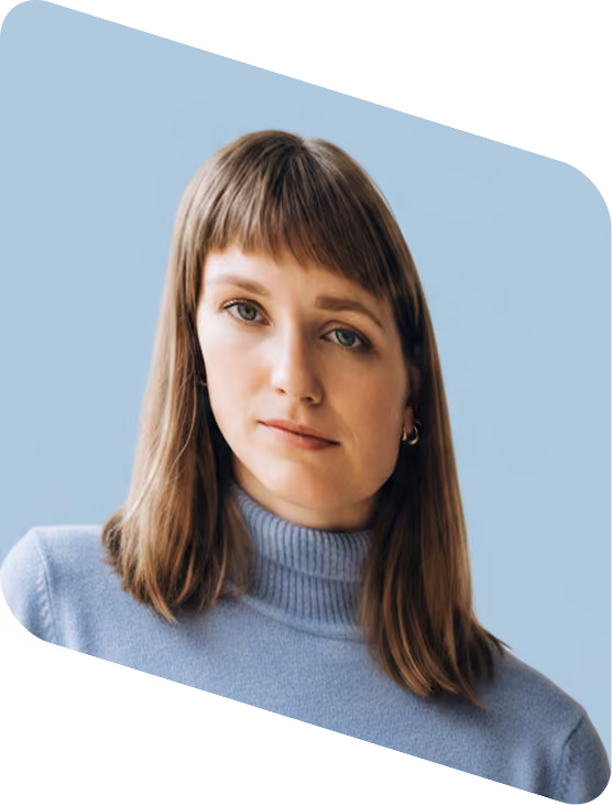 Woman with straight brown hair wearing a light blue turtleneck sweater against a light blue background.