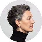 Profile of a mature woman with gray hair wearing a black turtleneck and hoop earrings.