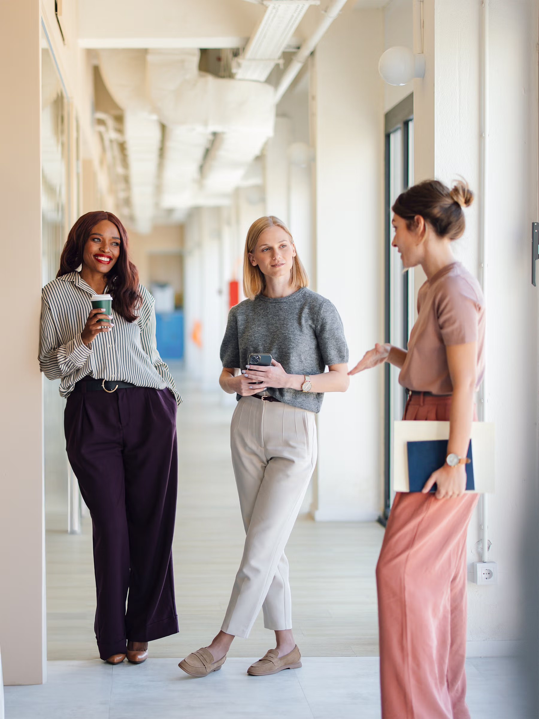 Team members working together on digital content in a collaborative in an office corridor