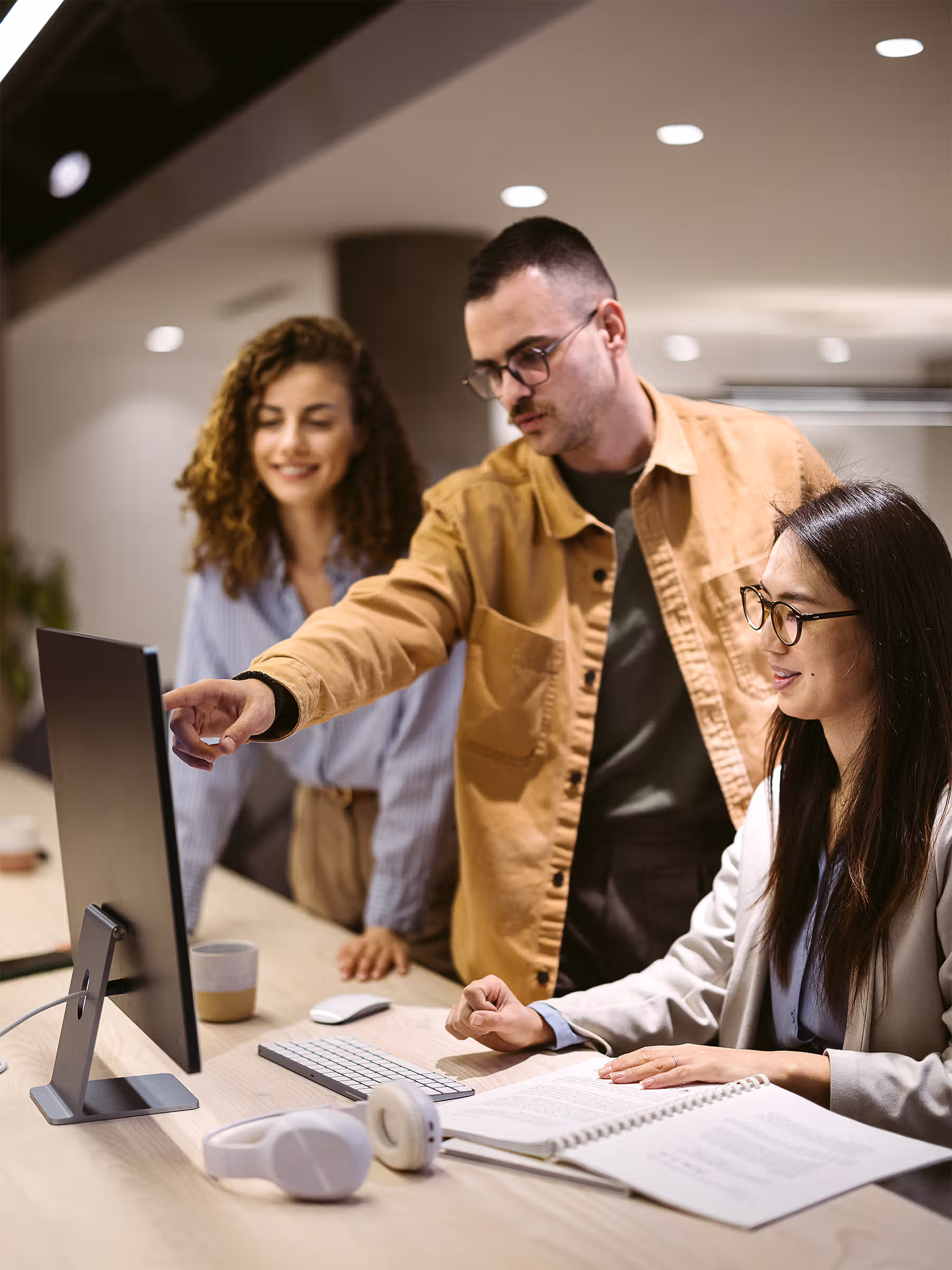 Professionals collaborating at a desk while reviewing information on a desktop computer.