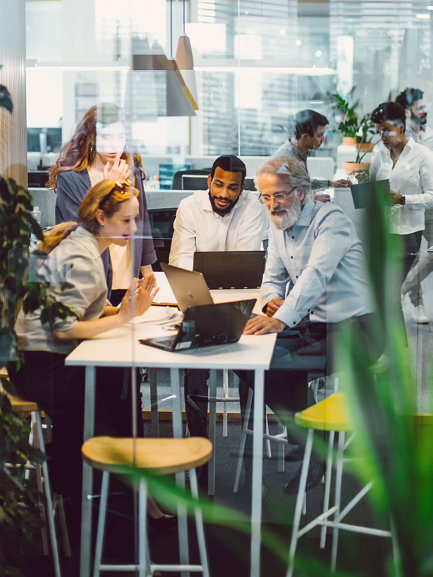 Three professionals collaborating around a desktop computer in a modern office environment.