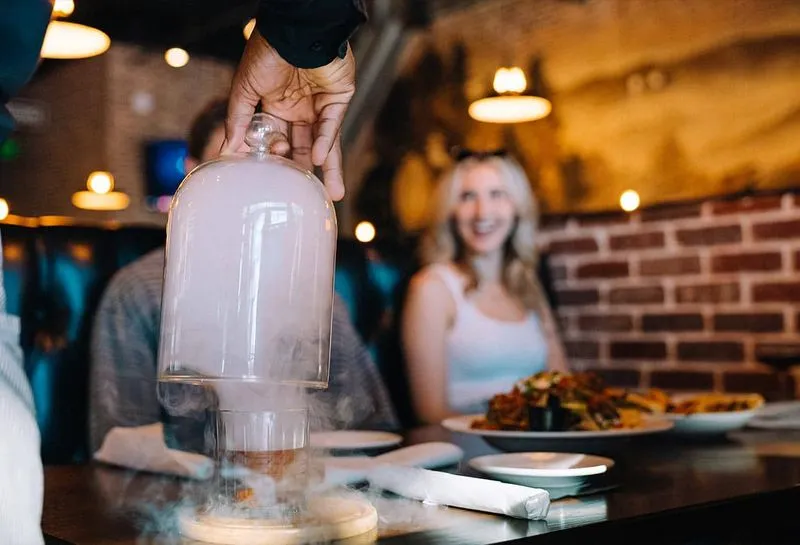 A waiter presenting a smoking drink to customers at Junction 35 Spirits in Pigeon Forge, Tennessee.