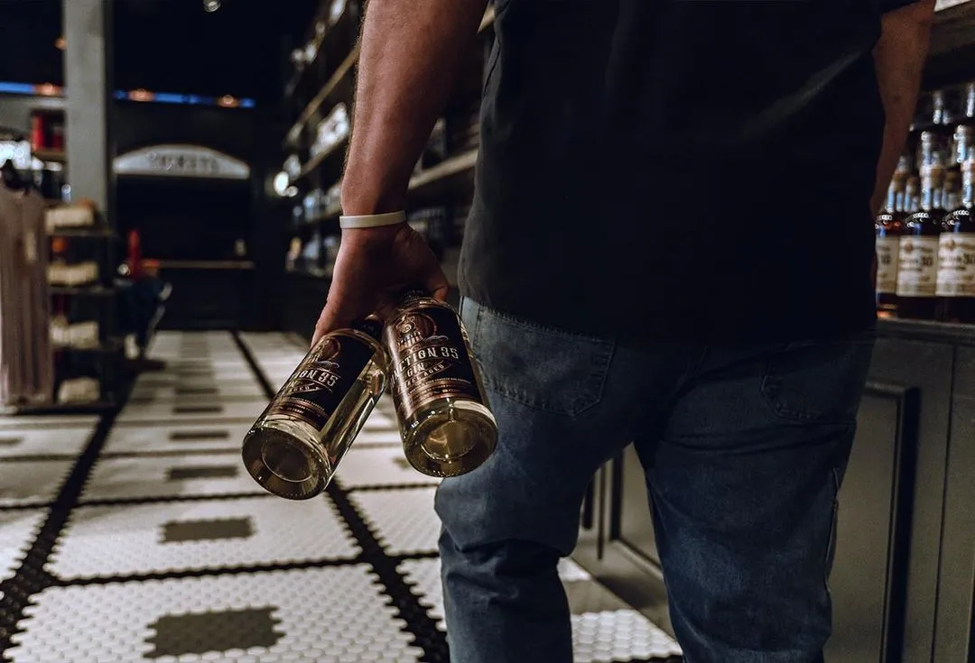 A man carrying two bottles of Junction 35 Whiskey