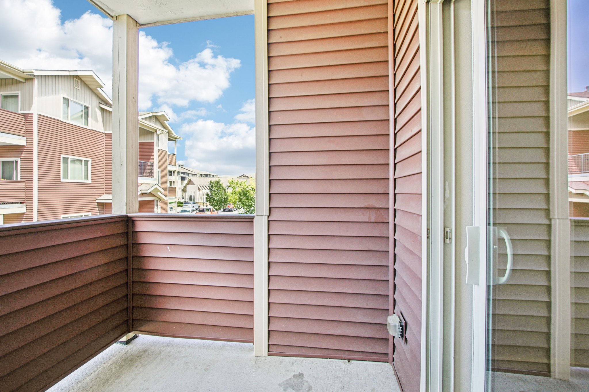 Covered private balcony with sliding glass door and outdoor living space at Copper Peak Apartments.