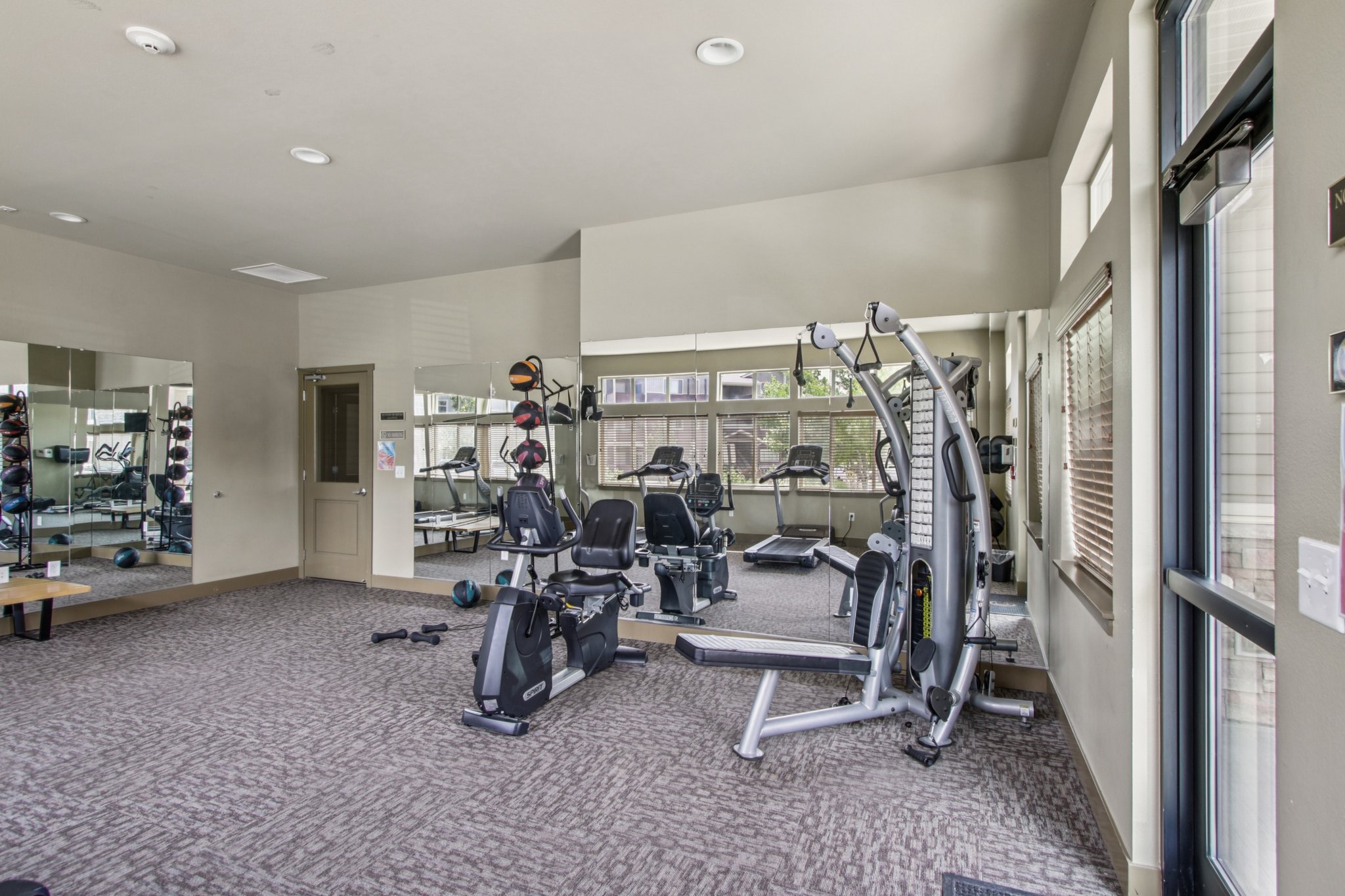 Fitness center at Copper Peak Apartments featuring treadmills, ellipticals, cardio equipment, and large windows.