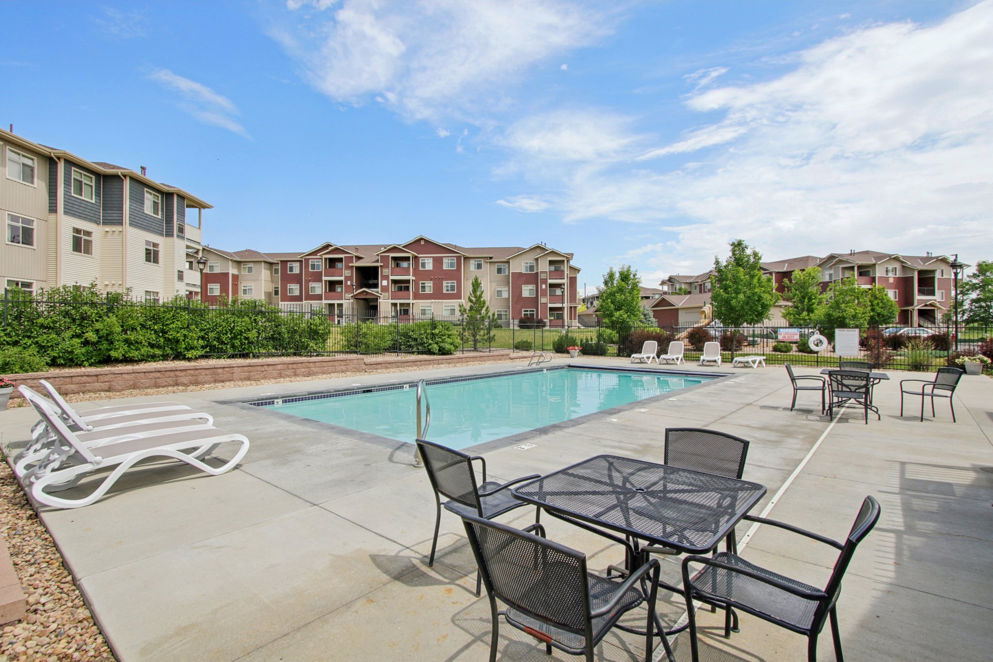 Community swimming pool with sundeck, lounge seating, and open outdoor recreation space at Copper Peak Apartments.