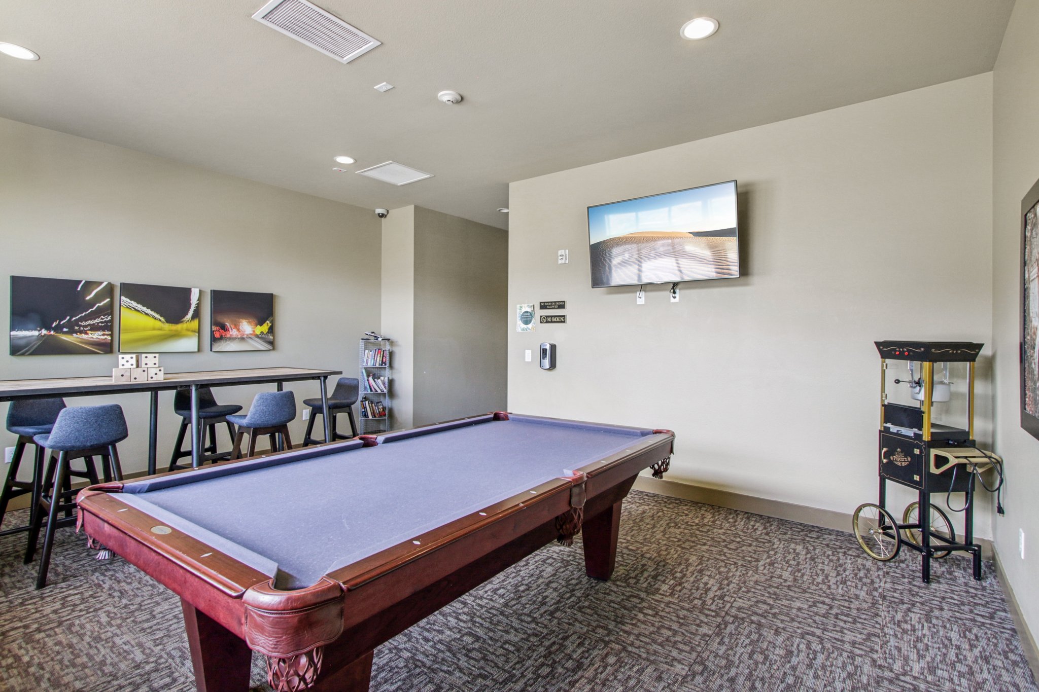 Resident clubhouse game room with pool table, high-top seating, television, and community gathering space at Copper Peak Apartments.