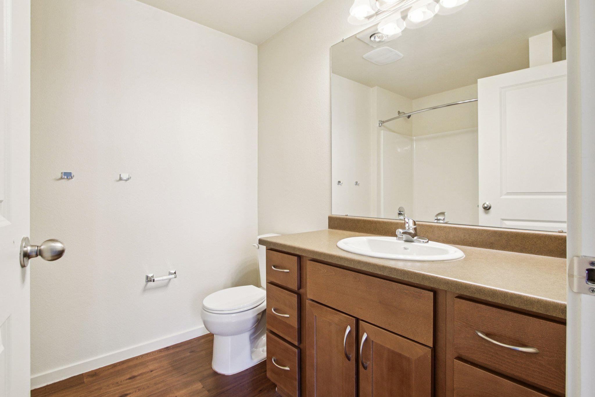 Primary bathroom with oversized vanity, wood cabinetry, and full-size bathtub at Copper Peak Apartments.