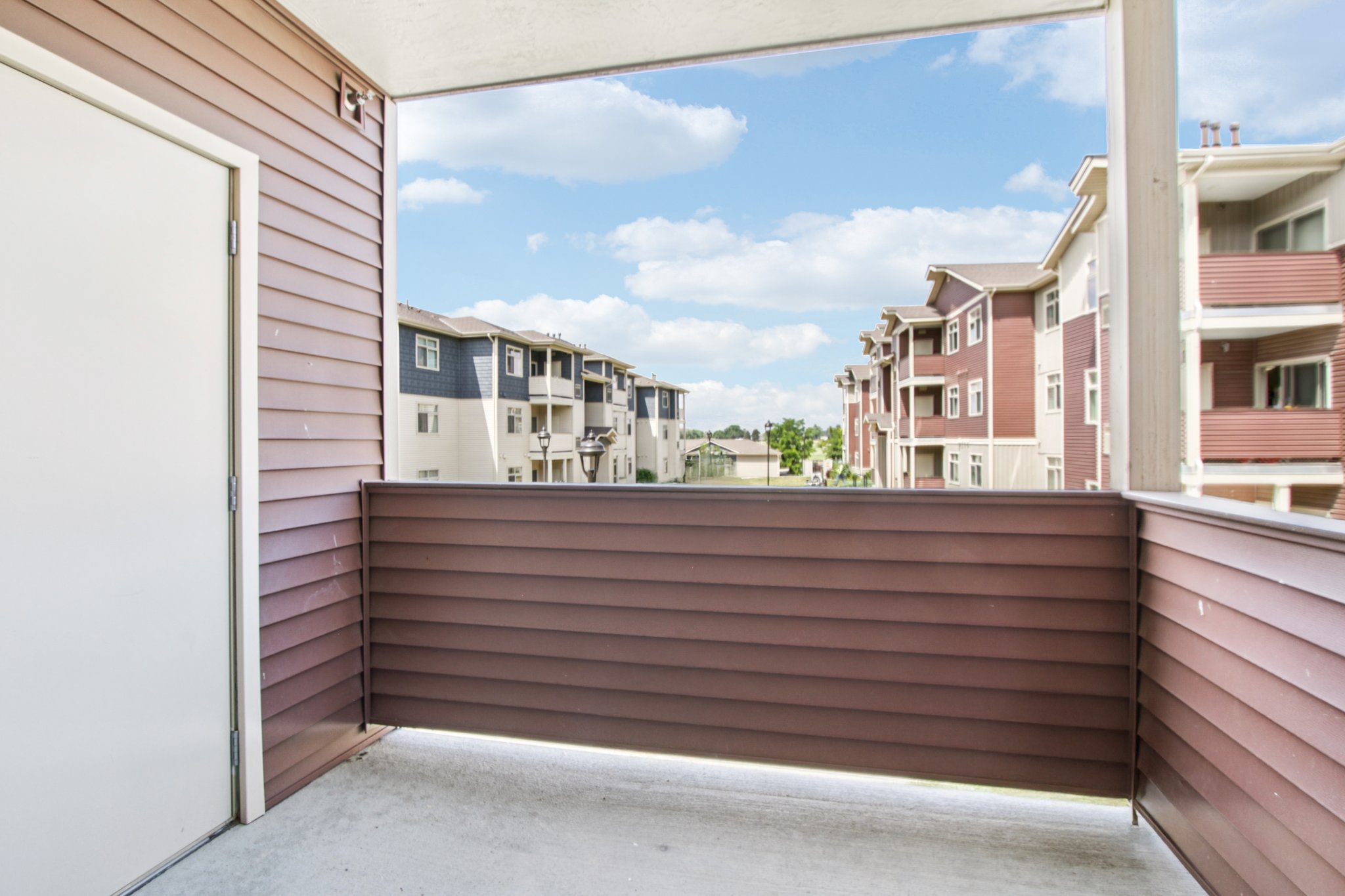 Private covered patio with storage overlooking the landscaped grounds and apartment buildings at Copper Peak Apartments.