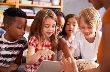 Four students gathered around a tablet smiling together