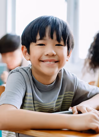 Smiling elementary student seated at a classroom desk