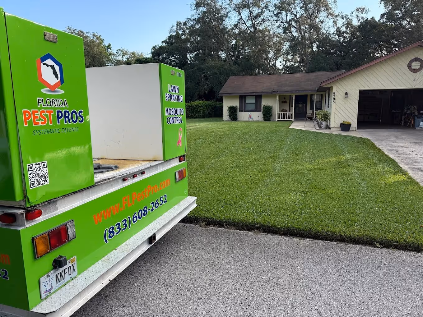 Green Florida Pest Pros truck parked on a residential street in front of a house with a neatly mowed lawn.
