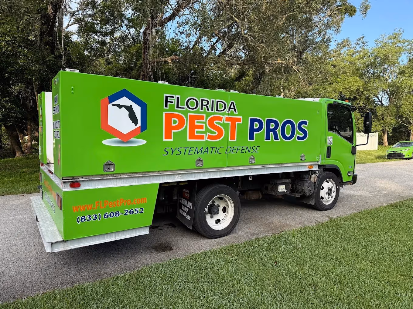 Bright green Florida Pest Pros truck parked on a residential street with phone number and website on the side.