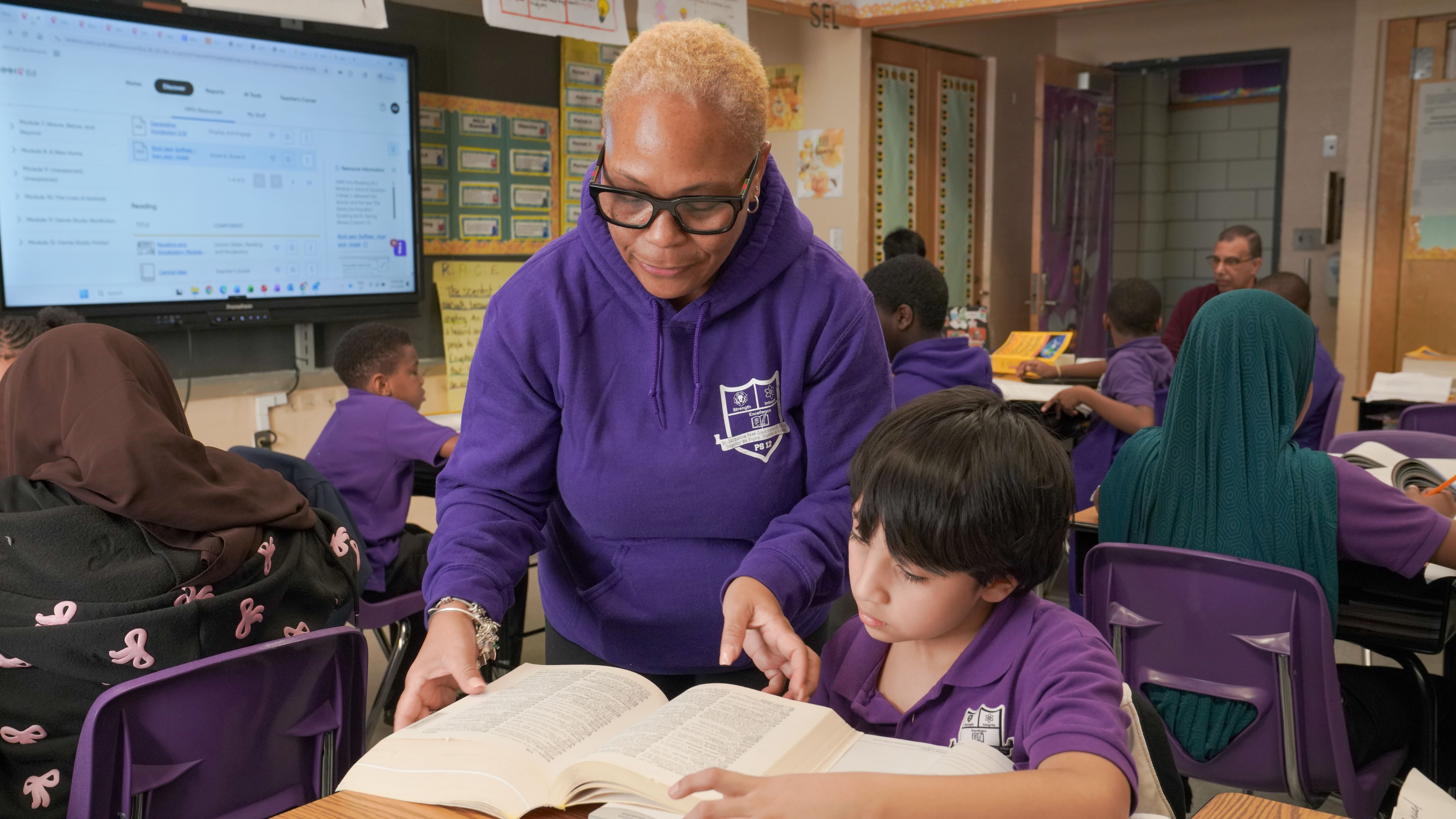 A teacher attentively helps a young boy 