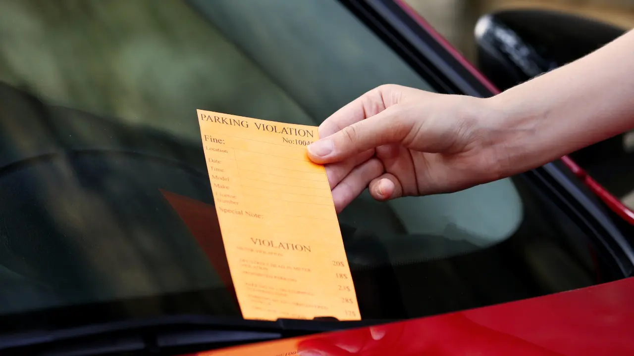 person lacing a note on a car windscreen