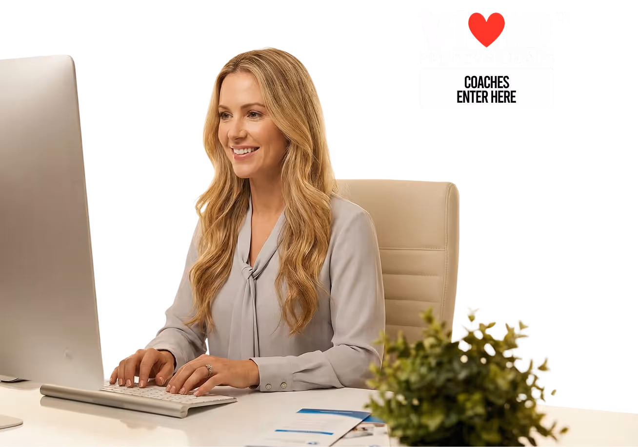 Smiling woman with long blond hair typing on a keyboard at a desk with a computer and plant.
