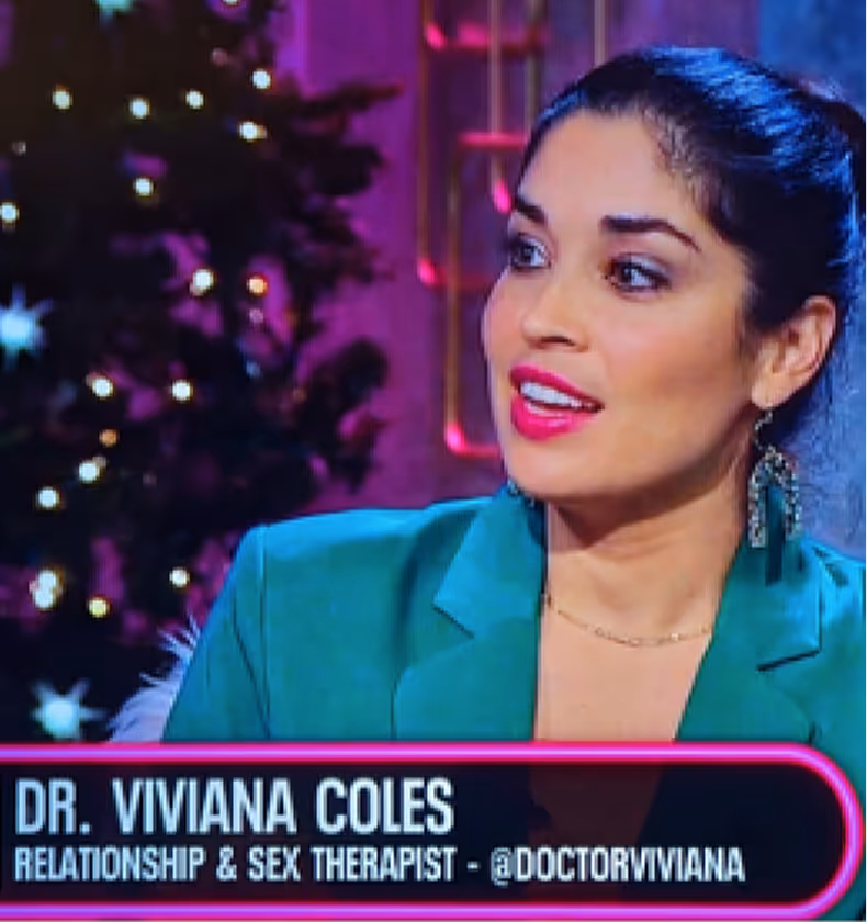 Dr. Viviana Coles, relationship and sex therapist, speaking on a television show with a decorated Christmas tree in the background.