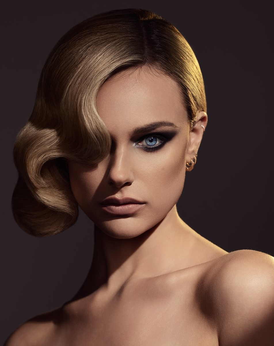 Professional stylist makeup and hair styling on woman with smoky eye and wavy blonde hair