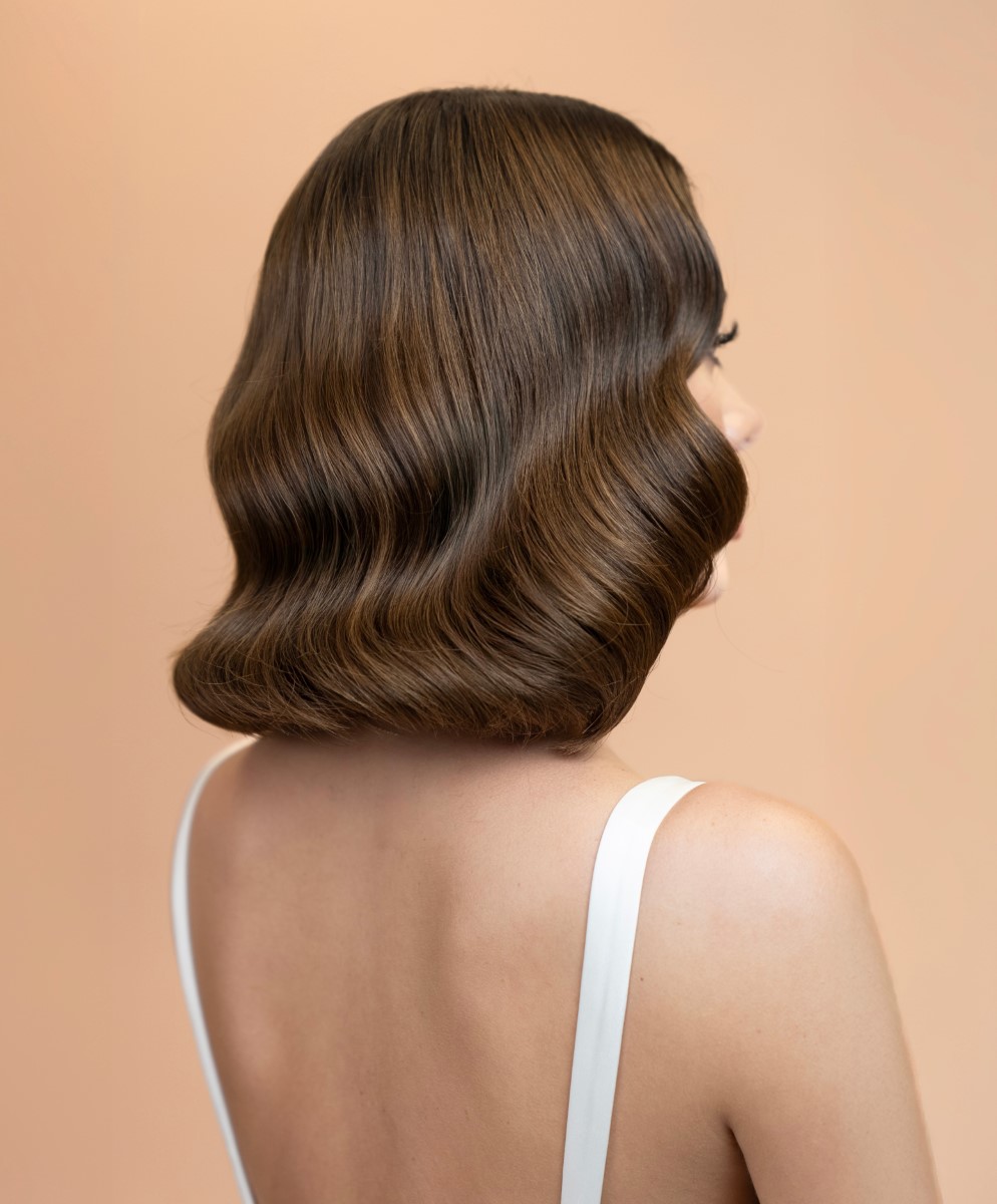 Professional stylist-created wavy hair and flawless makeup on woman from behind