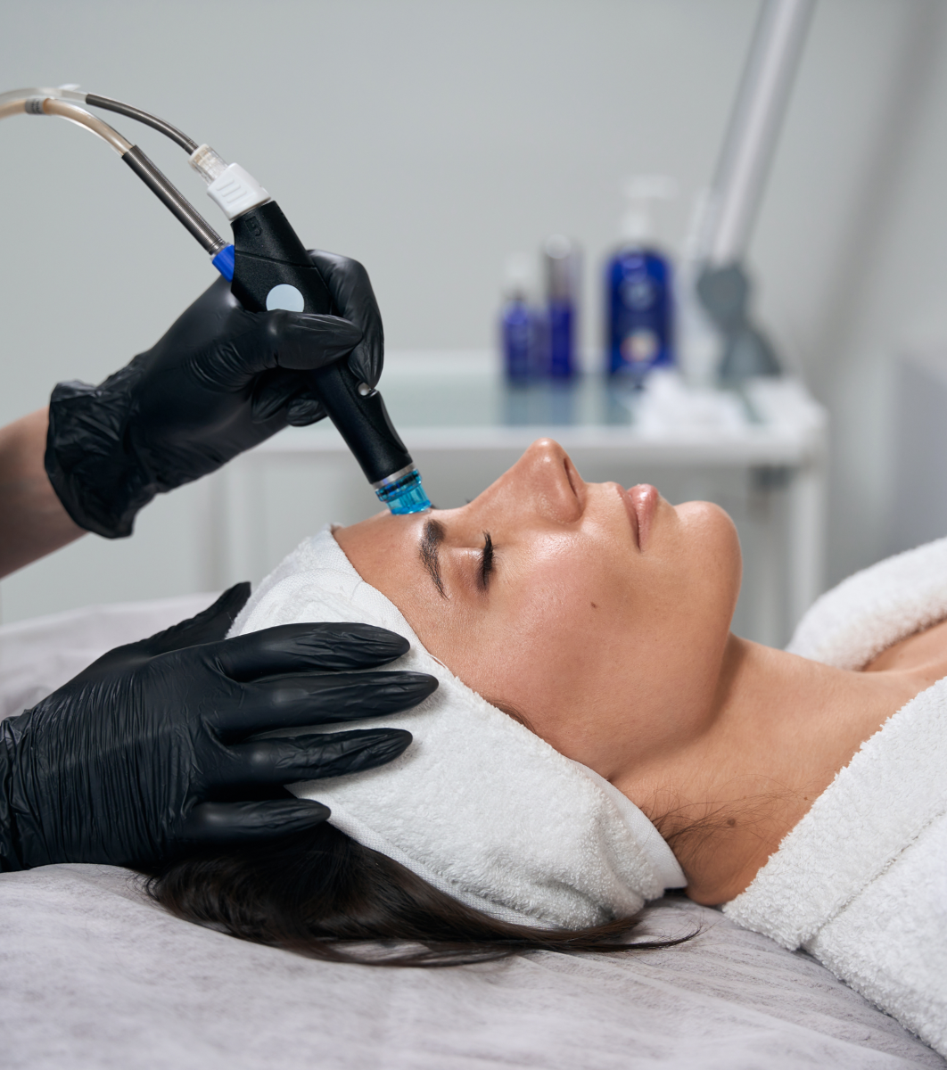 Aesthetician using microdermabrasion device for facial skincare treatment in clinic