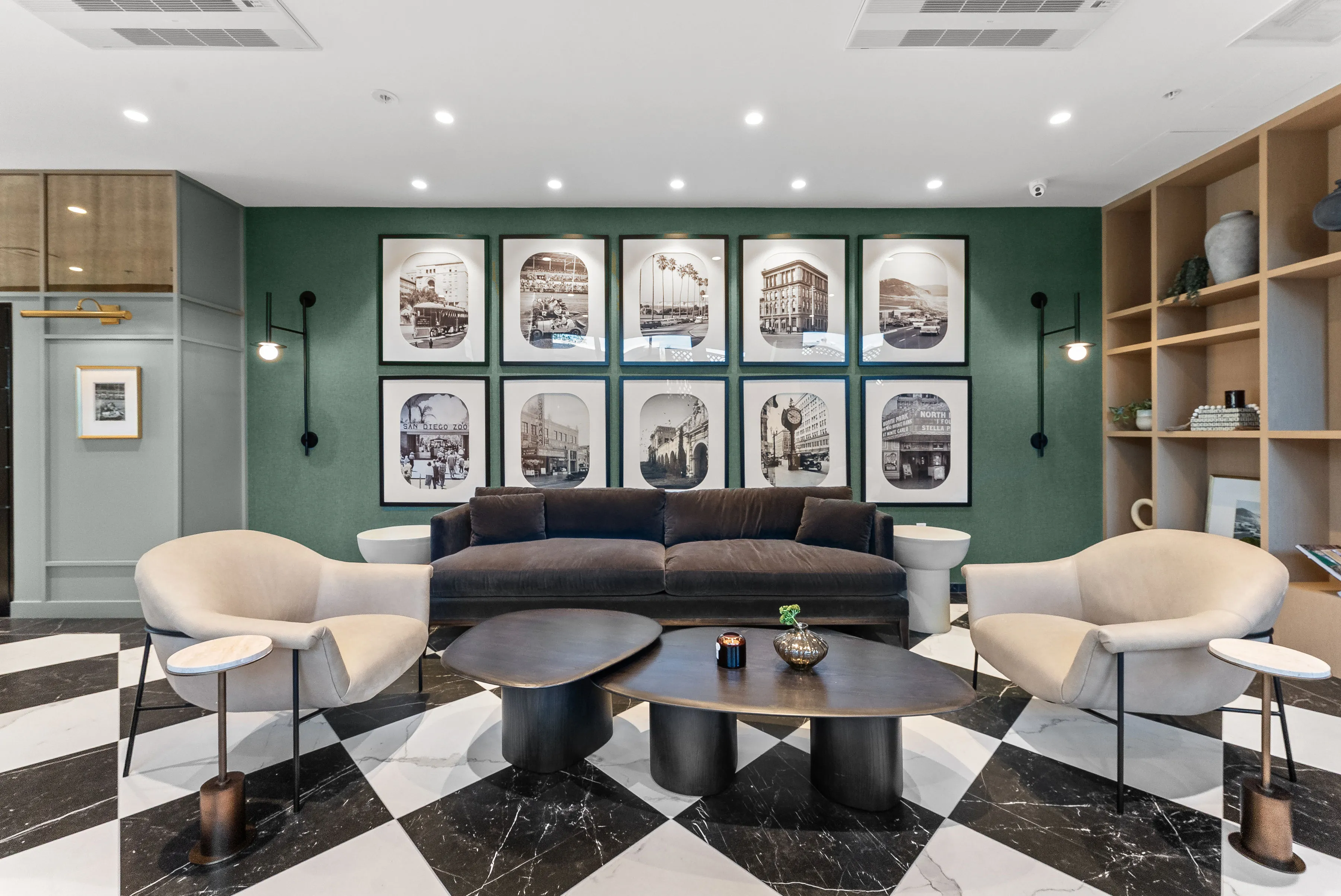 Modern lounge with gray sofa, two beige chairs, black-and-white checkered floor, and framed photos.