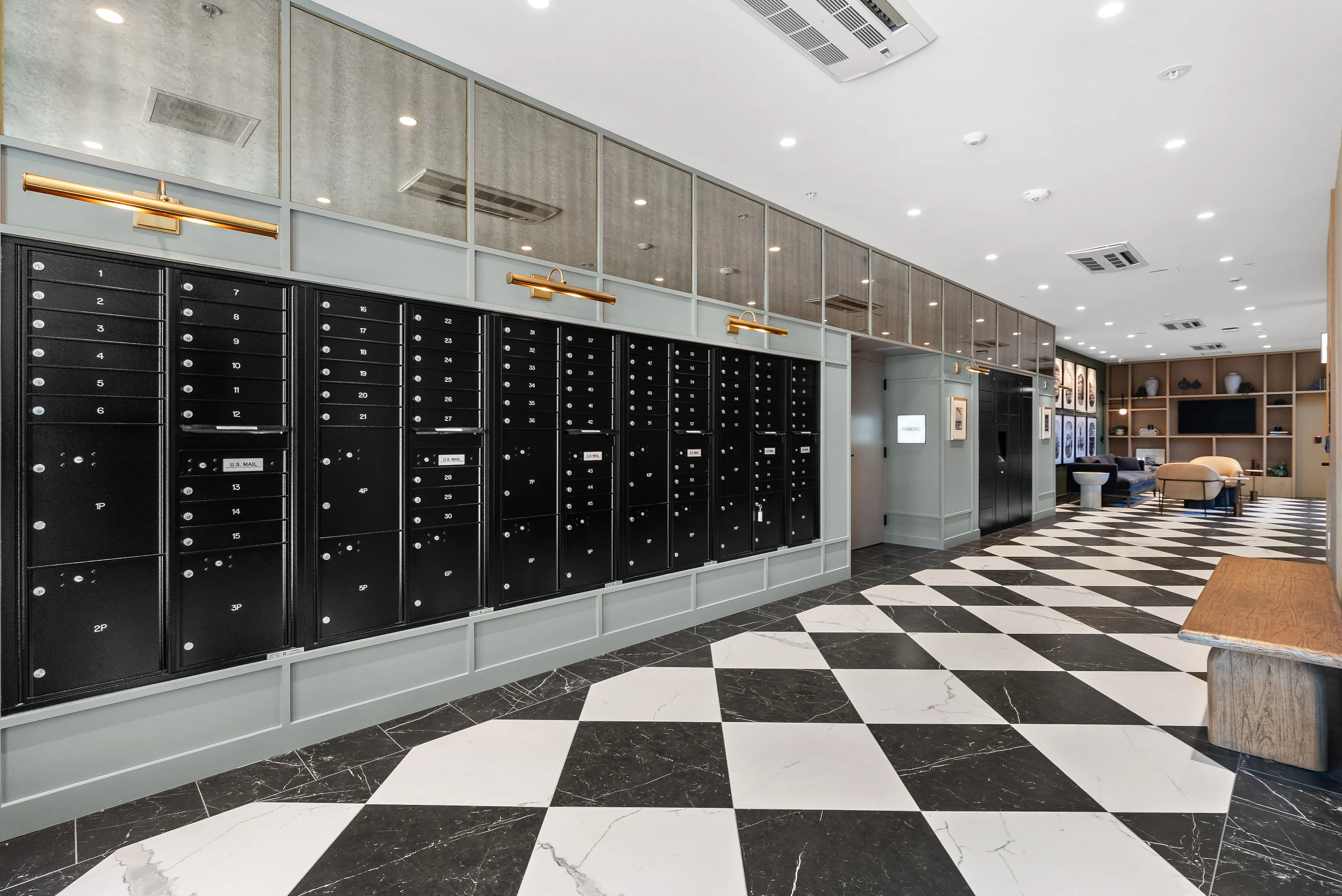 Modern lobby with black mailboxes on wall, checkered black and white floor, seating area in background.