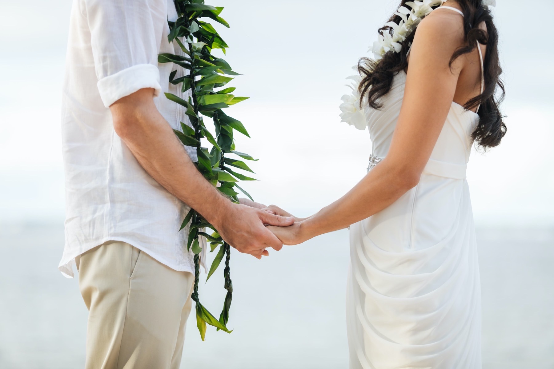 Man and Woman holding hands wearing Leis.